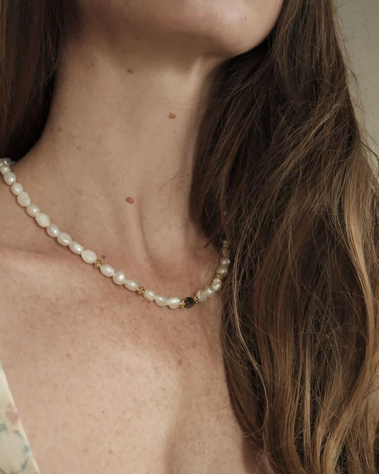 Collier en perles d'eau douce et une perle de labradorite, espacés de perles dorées à l'or fin, porté sur femme