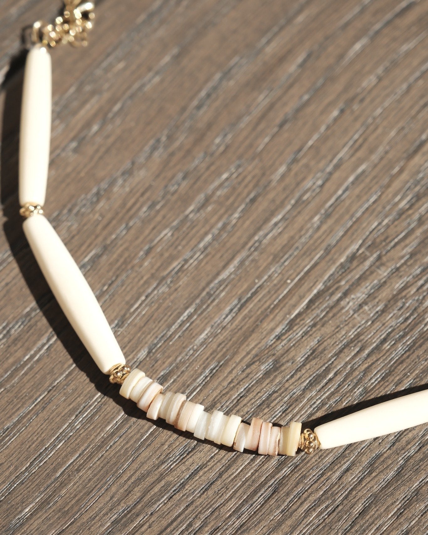 Collier en perles d’os et coquillages fins – détail sur fond bois naturel – Atelier Veda